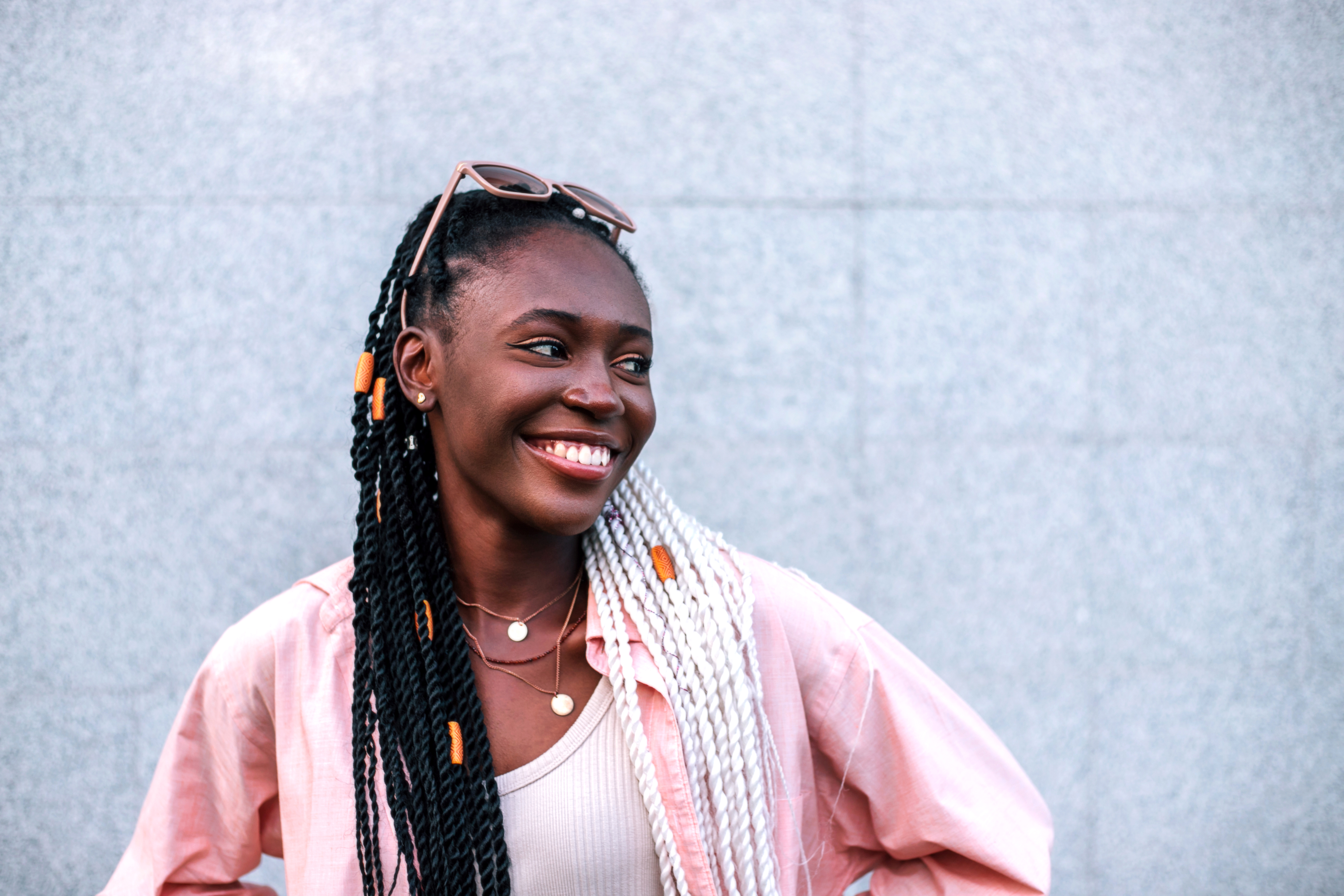 Young black braided woman smiling outdoors.