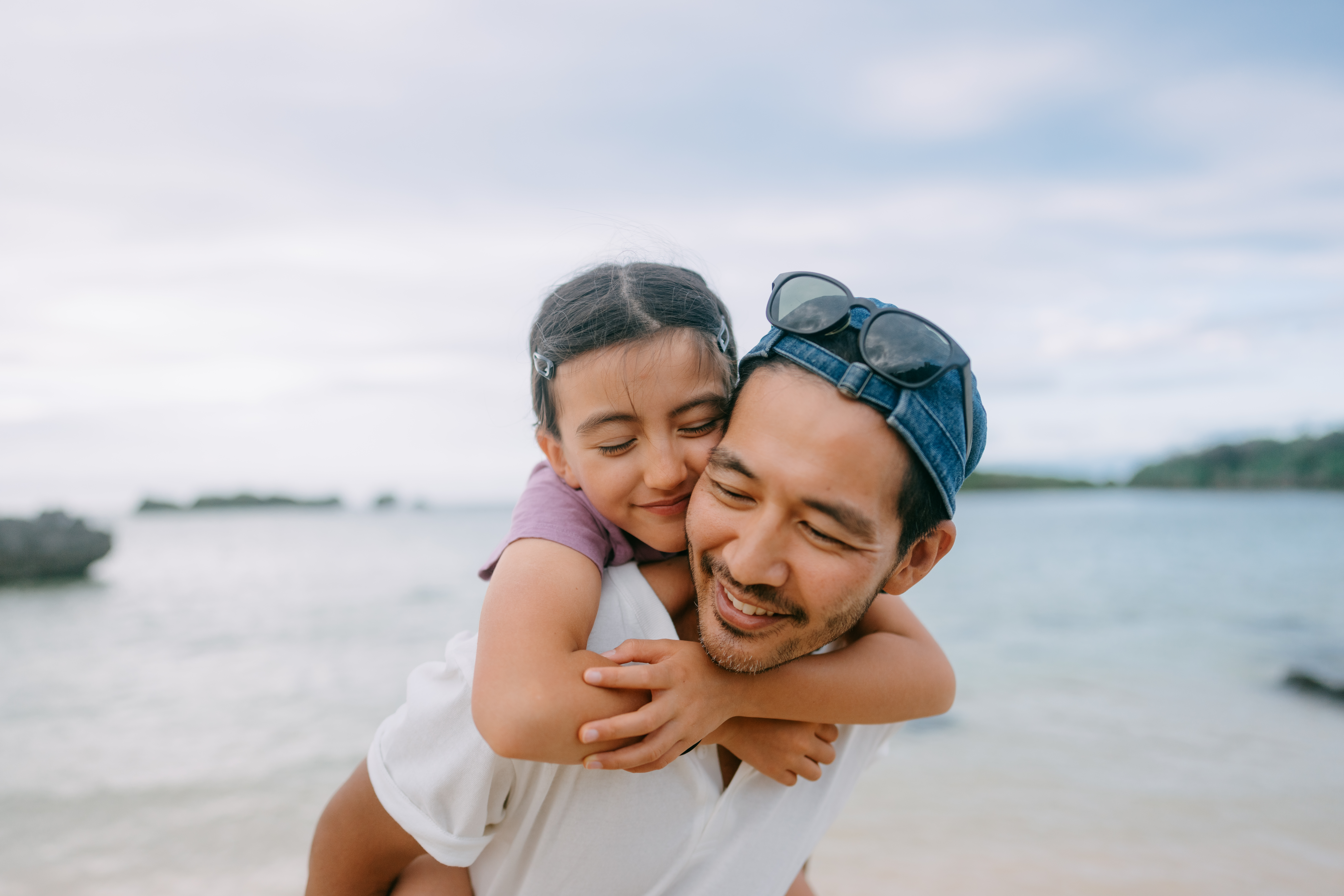 Father giving piggyback ride to young daughter on beach