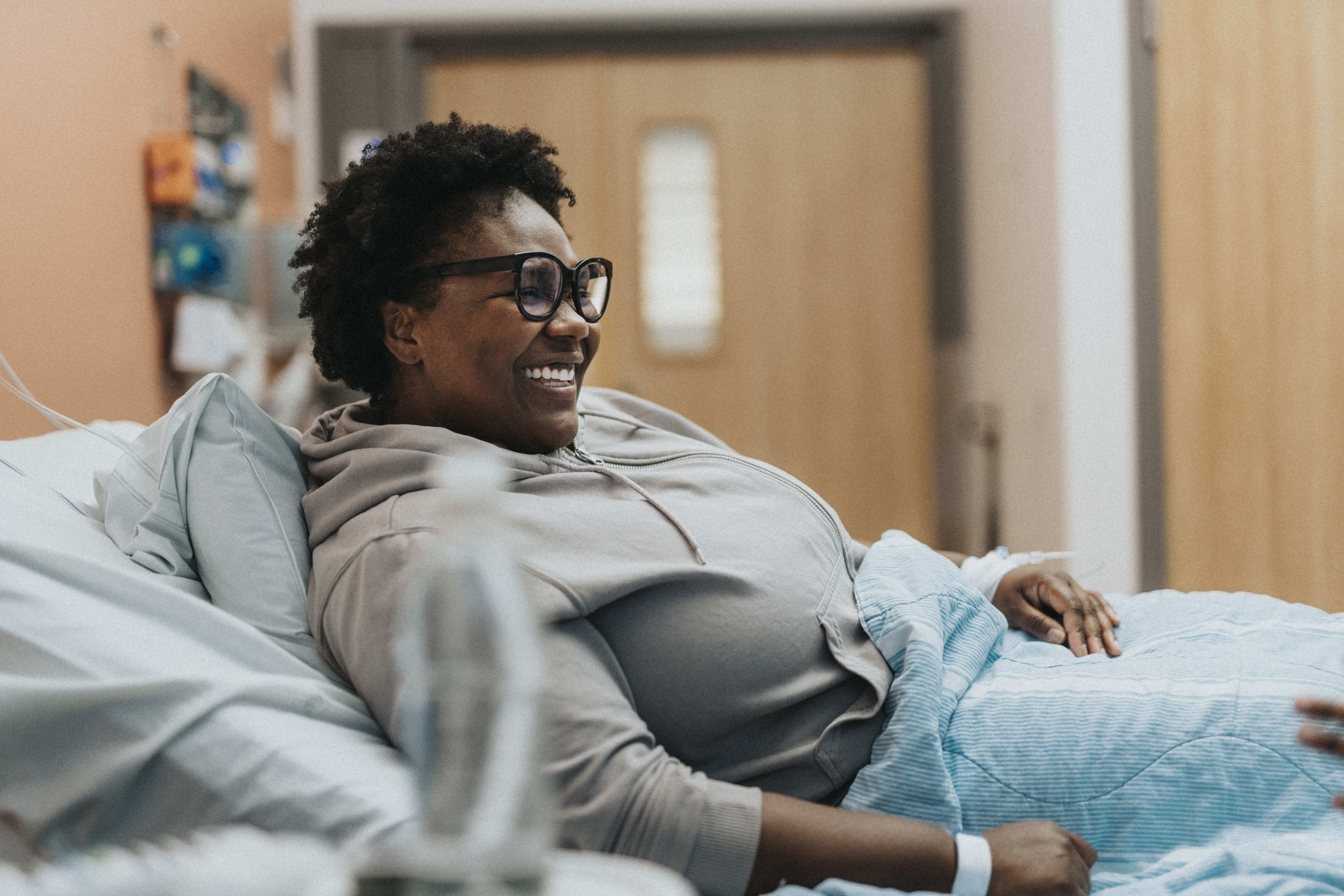 Happy female patient reclining on bed in hospital ward
