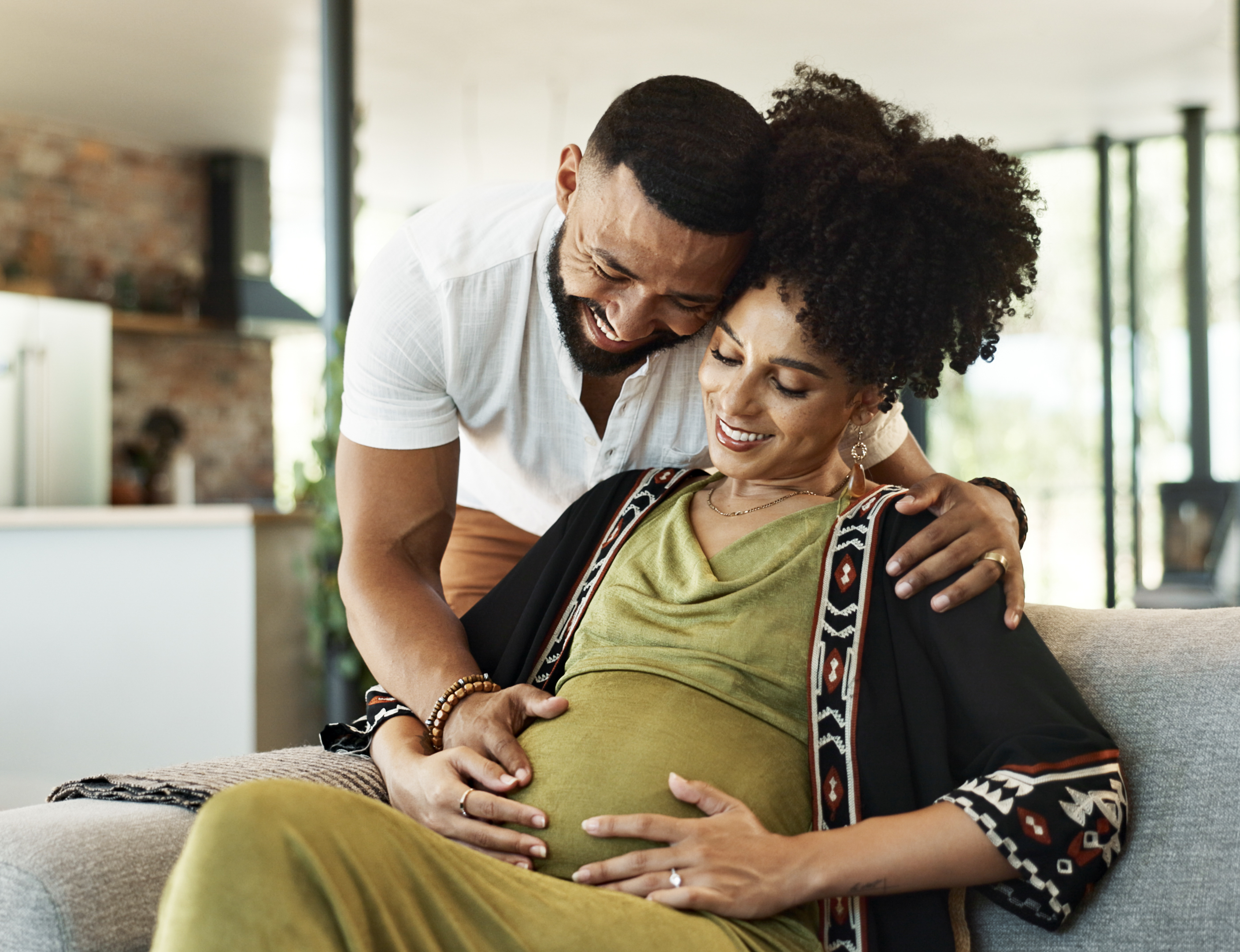 Pregnant, couple and woman on couch with bonding, tummy touch and support with maternity and motherhood. Future parents, affection on sofa and healthy pregnancy with embrace and excited for baby