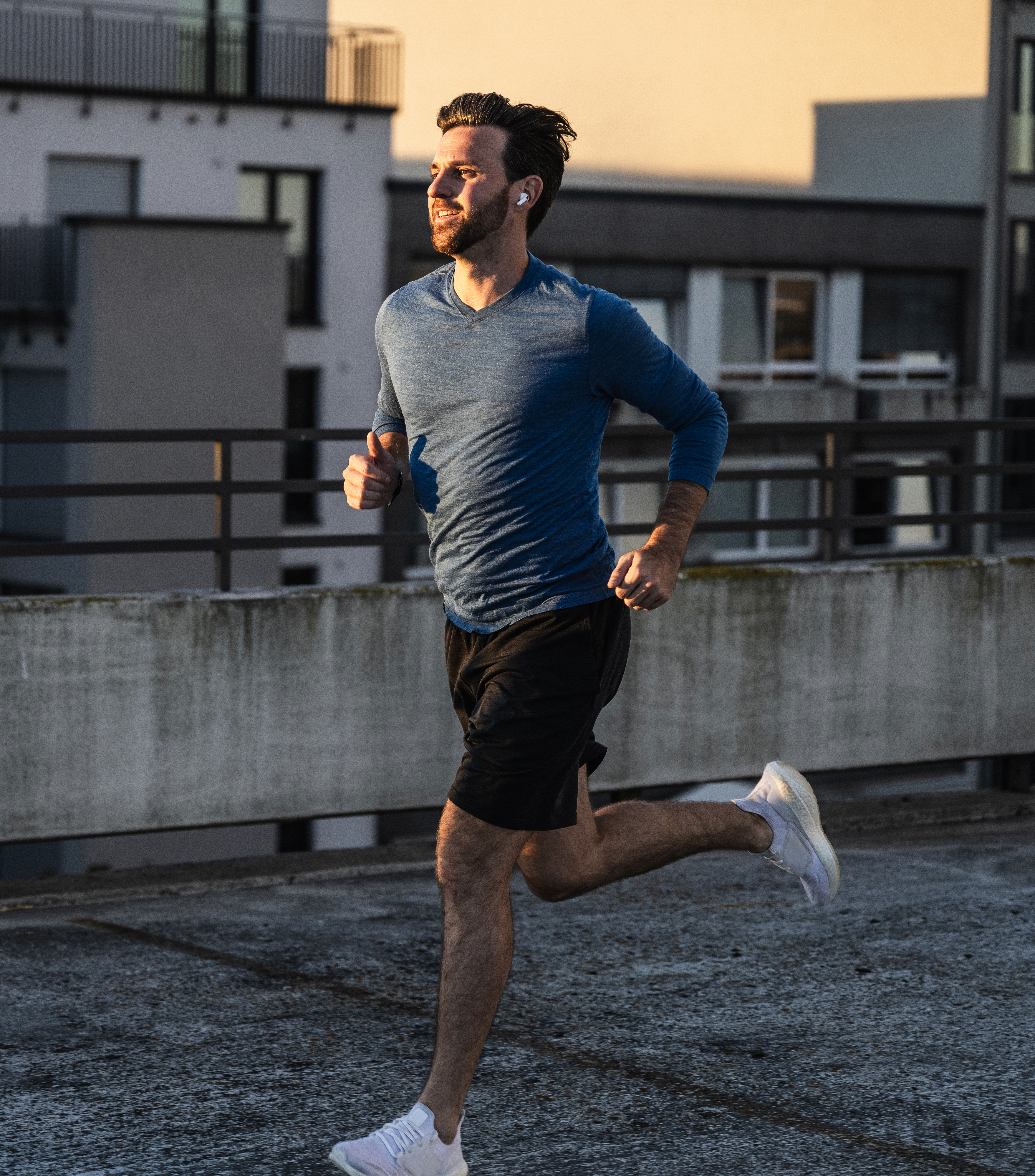 Active man running near railing on terrace at sunset